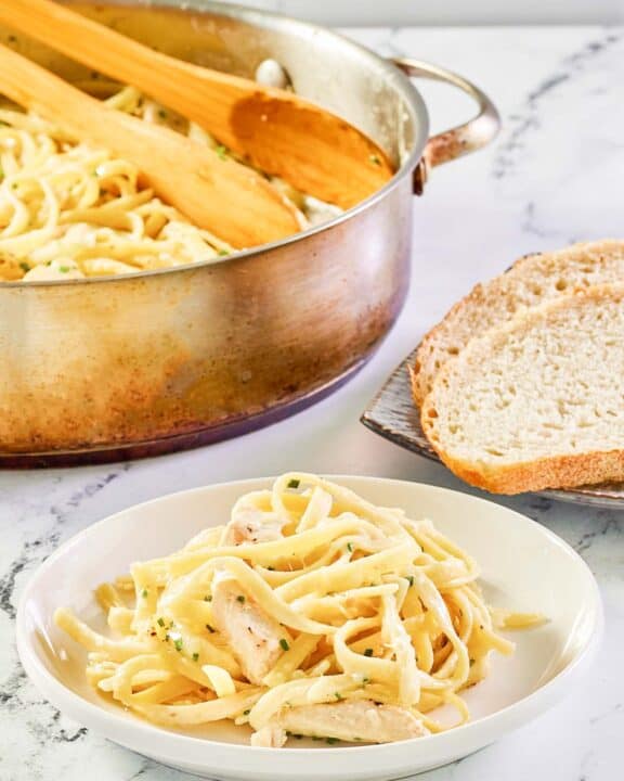 Chicken alfredo in a pot and a serving on a plate.