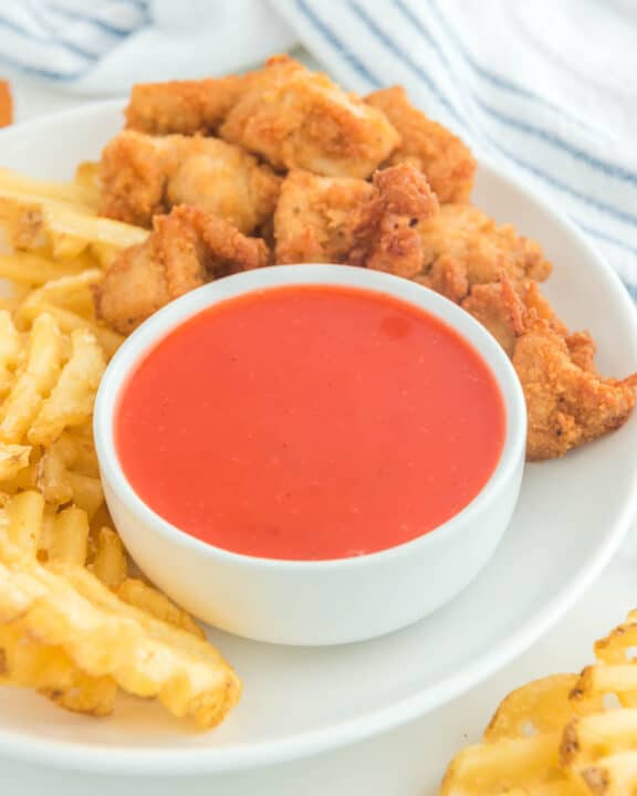 Copycat Chick Fil A Polynesian sauce in a bowl on a plate with chicken nuggets and waffle fries.