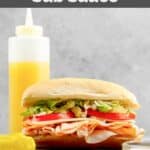 A sub sandwich and homemade Mr. Submarine sub sauce in a bottle behind it.