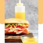 Homemade Mr. Submarine sub sauce in a bowl and squeeze bottle and a sandwich.
